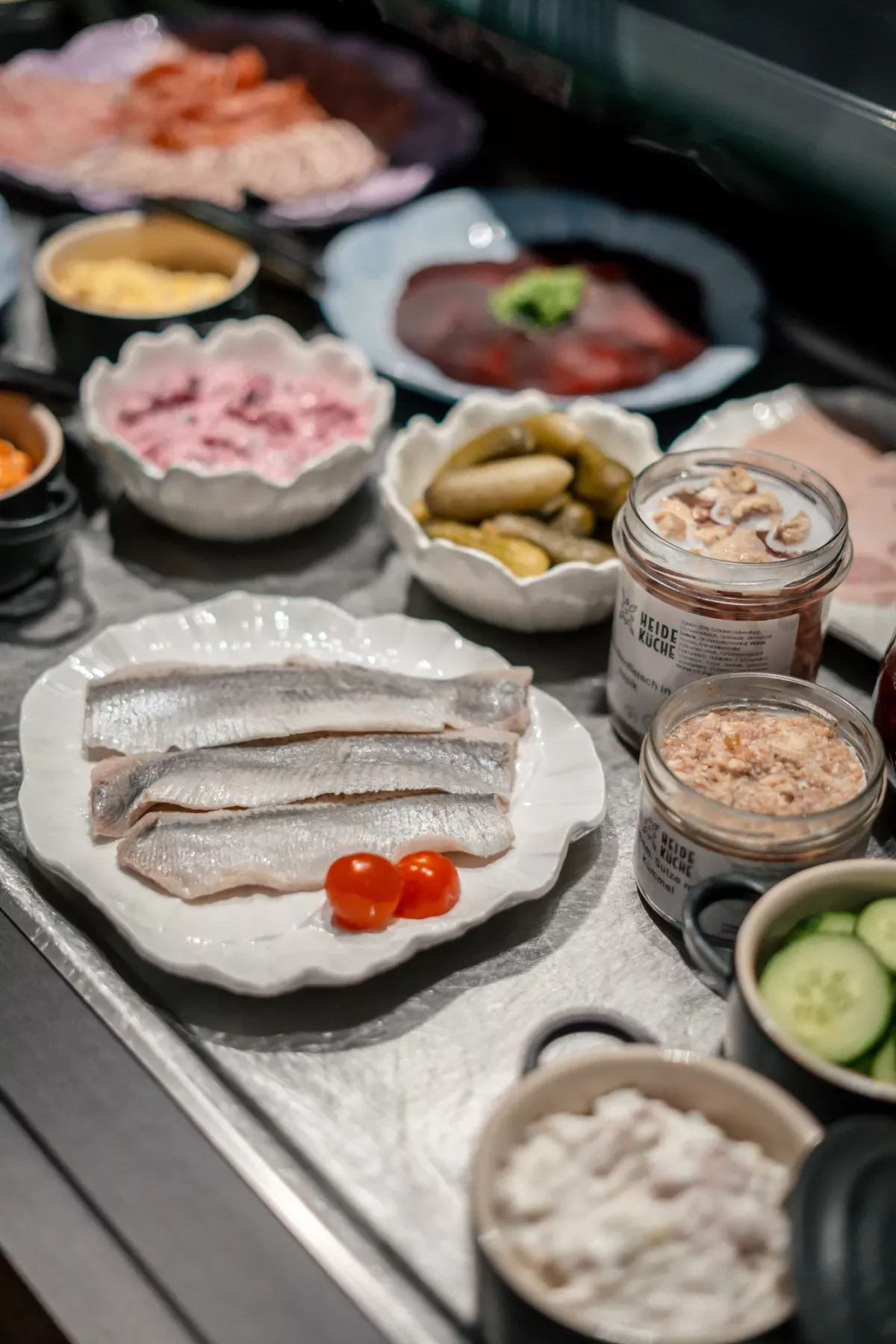 Frische Fischfilets auf wei&szlig;em Teller mit Tomaten und verschiedenen Zutaten wie Meerettich, Gurken und Fisch-P&acirc;t&eacute; als Fr&uuml;hst&uuml;cksbuffet.
