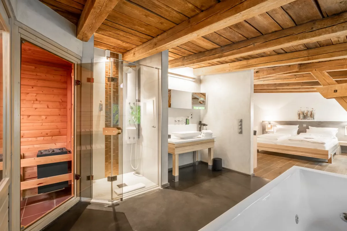 Modernes Badezimmer mit Sauna, Dusche, Doppelwaschbecken und Schlafbereich mit Holzdecke und Betonboden.